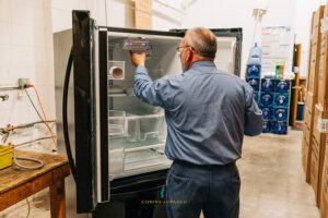 man adjusting fridge in warehouse