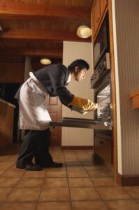 Side profile of a mid adult man cooking food in an oven