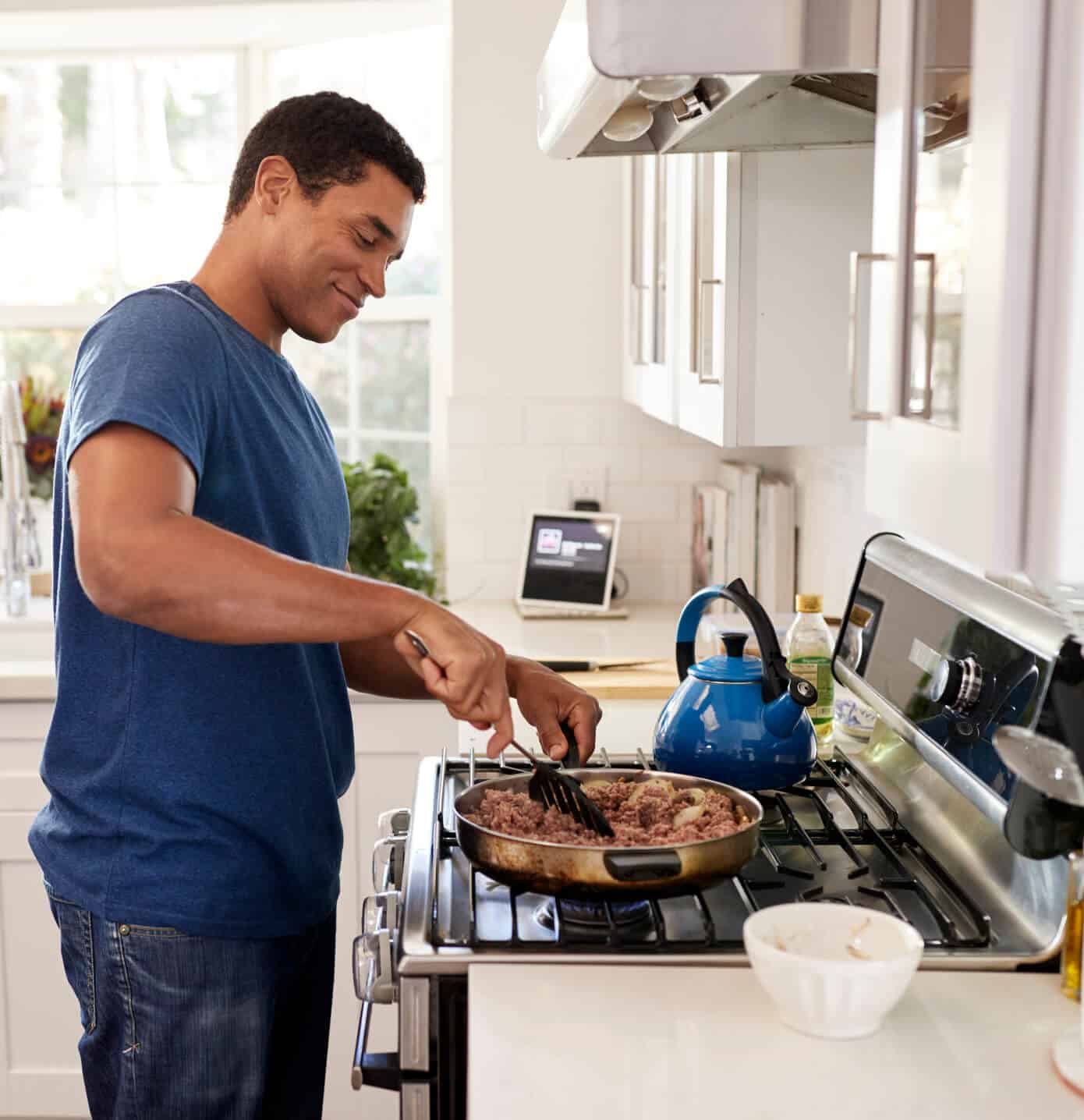 A man in Baltimore, MD is happily cooking dinner after stove & cooketop repair from Landers Appliance.