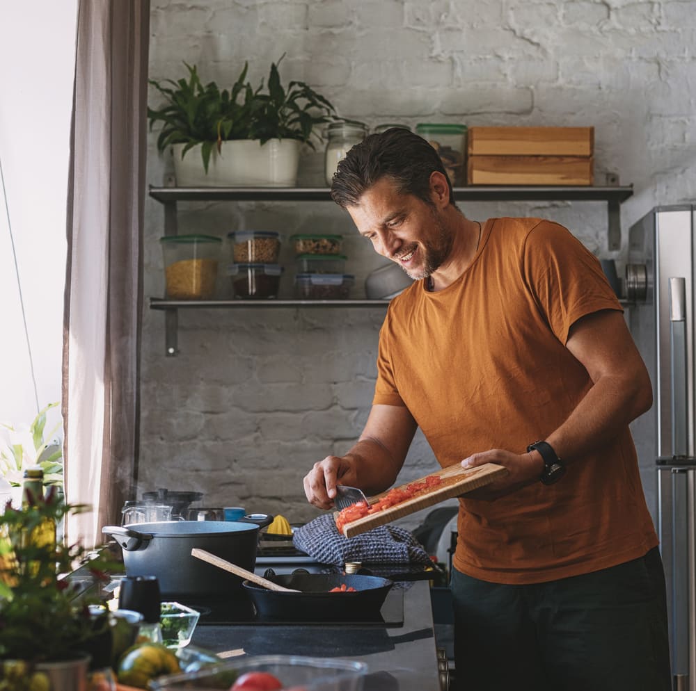 A man is back to cooking in his kitchen after Montgomery County cooktop repair services from Landers Appliance.