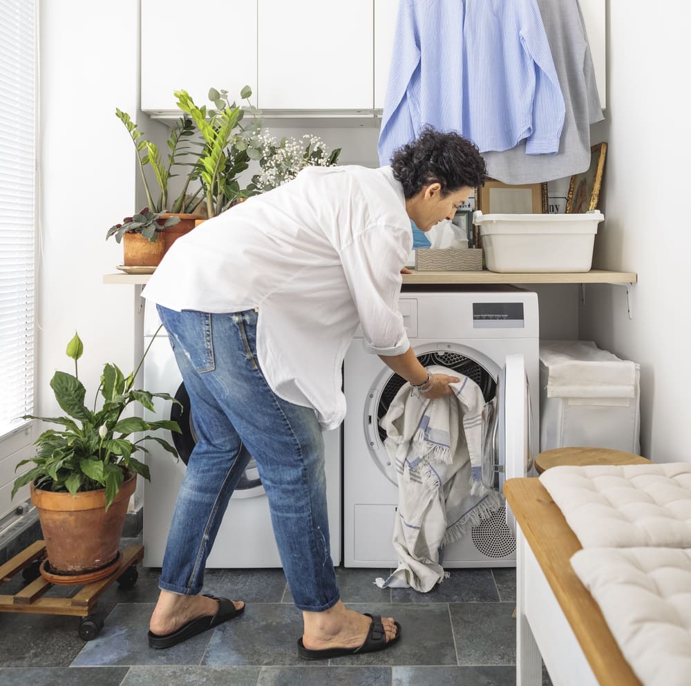 A woman finishes loading her washer after reliable Rockville and Montgomery County washing machine repair from Landers Appliance.